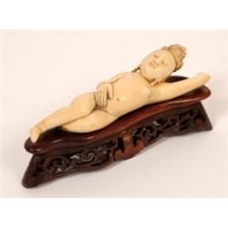 A 19th Century Japanese Carved Ivory Medicine Lady, lying on her back, on a pierced hardwood stand (