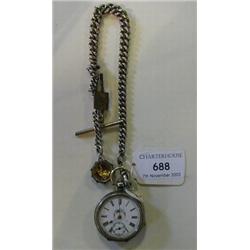 An Open Face Pocket Watch, with enamel dial and Roman numerals, in a white metal case, and silver wa