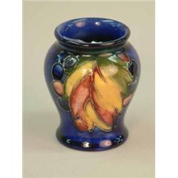 A Moorcroft leaf and berry pattern blue ground vase 3.25 ins....