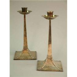 A pair of Edwardian arts and crafts silver candlesticks, with circular drip pans and tapered squa...
