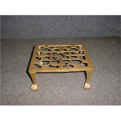 Un porte-plat du 19e Siècle en laiton ajouré sur des pieds griffes....