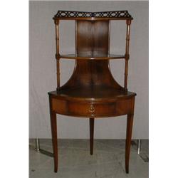 Une étagère d'angle en acajou, le plateau bordé d'une galerie ajourée au-dessus de deux planchett...