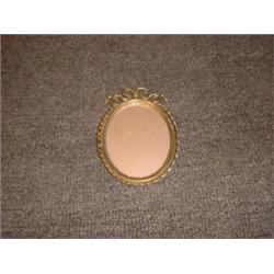 Un encadrement de photo ovale en métal doré à décor de rubans....
