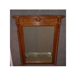 Un miroir rectangulaire en chêne, le fronton sculpté de feuillage, les montants en colonnes torse...