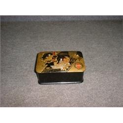 Un coffret en papier mâché à décor de personnages dans un bateau or et rouge sur fond noir....