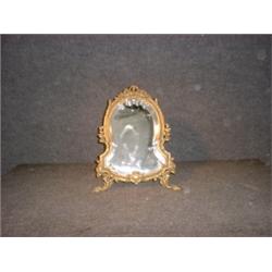 Un miroir de table de style Louis XVI en bronze à décor de rubans et de fleurs....