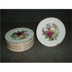 Un ensemble de 12 assiettes à dessert en porcelaine de Regency à décor de fruits sur fond vert....