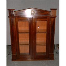 Une vitrine murale de style Empire en acajou munie d'un fronton triangulaire au-dessus de deux po...