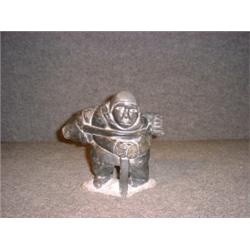 Une sculpture inuit en stéatite représentant un homme transportant un phoque sur son dos, signé....