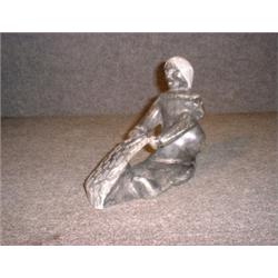 Une sculpture inuit en stéatite représentant un personnage nettoyant une peau....