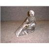 Image 1 : Une sculpture inuit en stéatite représentant un personnage nettoyant une peau....