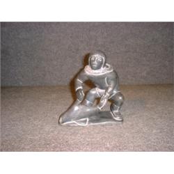 Une sculpture inuit en stéatite représentant un homme se saisissant d'un phoque, signé: "Adamie A...