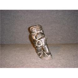 Une sculpture inuit en stéatite représentant un homme transportant un phoque....