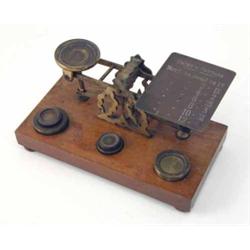 A late 19th Century S Mordan and Co postal scales, with gilt brass body and five weights on walnu...