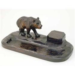 A Black Forest carved wood desk stand, modelled with a single bear, covered inkwell and pen well...