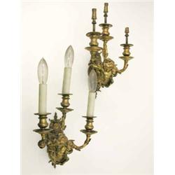 A pair of late 19th century gilt metal wall lights, each cast as a putto suspended by a large rib...