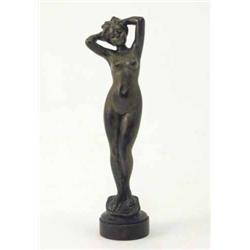 A bronze figure of a naked female, modelled with legs together and hands behind her head on circu...