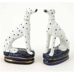 A pair of French porcelain dalmatians, each seated on oval, blue cushion base, one base cracked,...