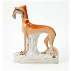 A Victorian Staffordshire pottery greyhound, painted in rust enamel, holding dead rabbit in jaw,...