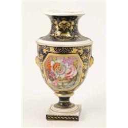 A Bloor Derby vase, painted with a panel of flowers against a gilded blue ground, on square pedes...