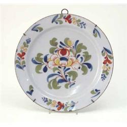 An 18th century delftware charger, probably Dutch, primitively painted with flowers in blue, gree...