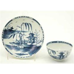 A rare Worcester tea bowl and saucer, painted in underglaze blue with the “candle fence pavilion”...
