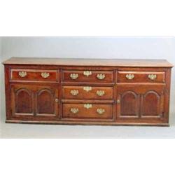 A mid 18th century oak dresser base, with five drawers and two doors, with double arch panels on...