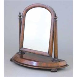 An early Victorian walnut toilet mirror, having arch topped cushion framed mirror with tapered co...