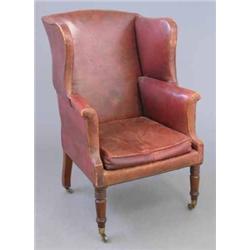 An early 19th century mahogany framed wing armchair, upholstered in deep maroon leather, raised o...
