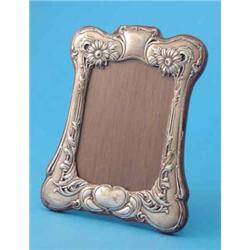 An Edwardian Art Nouveau silver photo frame, of serpentine rectangular form, decorated with flowe...