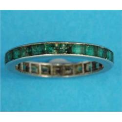 A white metal full eternity ring, set calibre-cut emeralds, size L½...