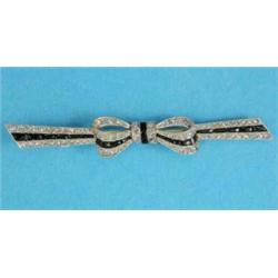 A gold ribbon brooch, set diamonds and calibre cut onyx...