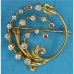 A gold open circle brooch, designed as a stylised floral spray set diamonds and rubies...