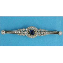 An Edwardian gold and platinum bar brooch, set with a central sapphire in a diamond set pierced w...