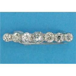A white gold bar brooch, set with a graduated line of 7 old brilliant cut diamonds...