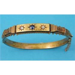 A Victorian 15ct gold hinged bangle, with wirework decoration, the front gypsy set with a sapphir...