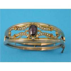 A Victorian gold openwork hinged bangle, the front set with an oval garnet and seed pearls...