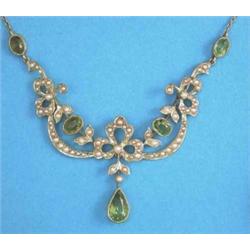 An Edwardian 15ct gold, peridot and seed pearl set necklace, designed as tied ribbons and swags,...