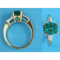 A gold emerald and diamond ring, the claw-set rectangular cut emerald flanked by tapered baguette...