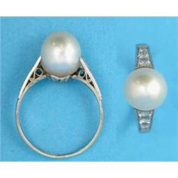 A white gold ring, set with a single pearl, the tapered shoulders set diamonds...