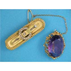 An oval amethyst brooch, in scrolled gold frame and a 15ct gold brooch with central buckle motif...