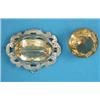 Image 1 : A circular citrine brooch, in plain gold frame and an oval citrine brooch in engraved silver scro...