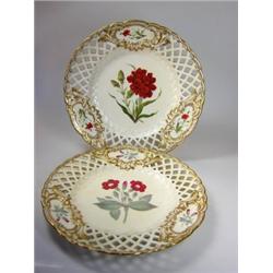 A pair of mid 19th century plates painted with cut flowers in gilt vignettes on the diamond lattice.