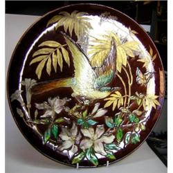 An early 20th century wall plaque, possibly by Theodore Deck, the treacle brown ground moulded with.