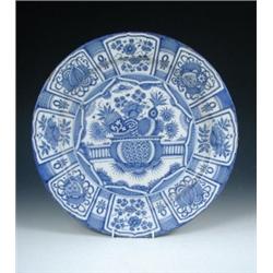A mid 18th century Delft blue and white charger painted in the kraak style, a bowl containing flowe.