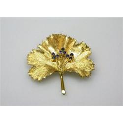 An 18ct gold brooch modelled as a leaf, the centre decorated with three sprigs of three sapphires,..