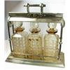 Image 1 : An electroplate three bottle tantalus, raised on a plain square base below a patent rolling bar loc.
