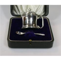 A silver mustard pot, maker CTB, Birmingham 1910, of plain spool shape with hinged cover and blue l.