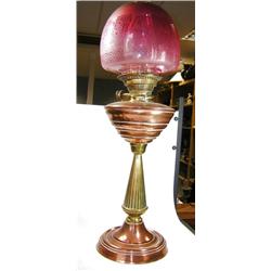 An early 20th century copper and brass oil lamp, the cranberry glass globe acid etched with a Paisl.
