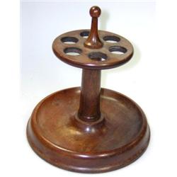 A turned rosewood pipe stand, a pawn shaped finial above a disc pierced to hold six pipes above gun.